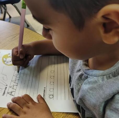 A student practicing letters